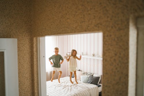 Happy Siblings Jumping on Bed