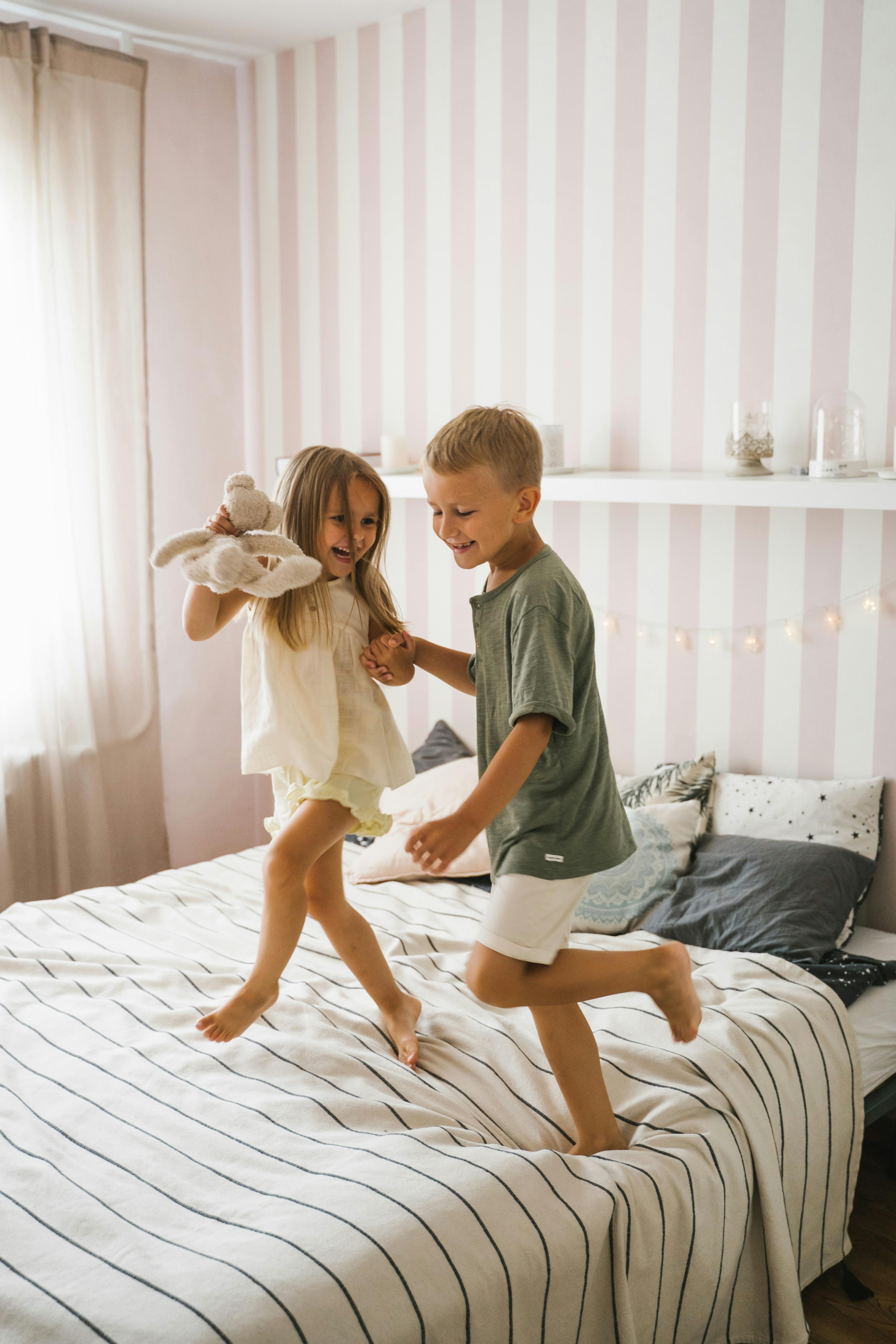 a happy boy and girl dancing on the bed