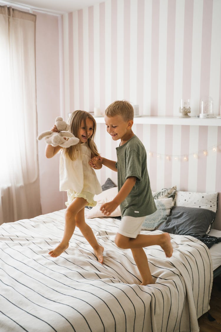 A Happy Boy And Girl Dancing On The Bed