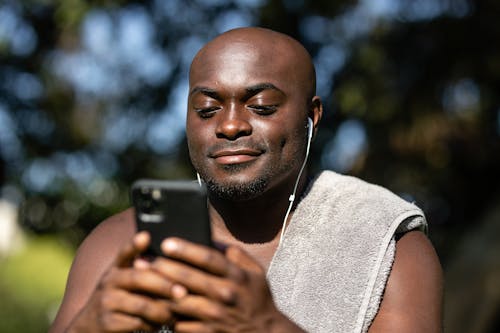 Close-Up Shot of a Man Listening to Music while Using a Mobile Phone