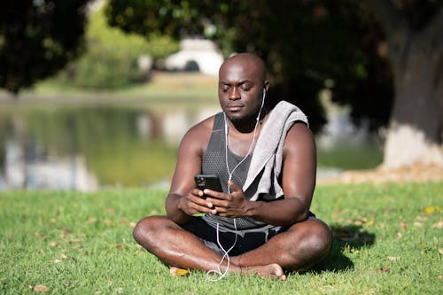 Free Man Sitting on Grass While Using Cellphone Stock Photo