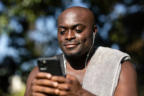 Close-Up Shot of a Man Listening to Music while Using a Mobile Phone