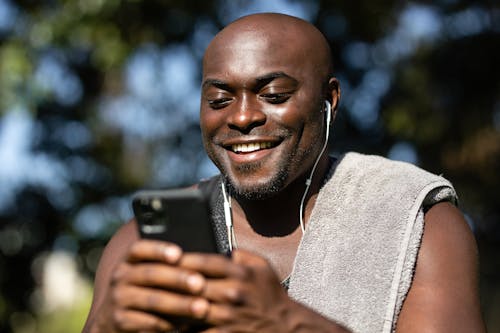 Free Close-Up Shot of a Man Listening to Music while Using a Mobile Phone Stock Photo