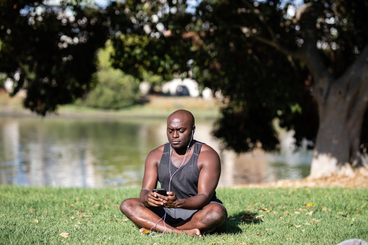 Person sitting outdoors with a smartphone in a calm, mindful posture
