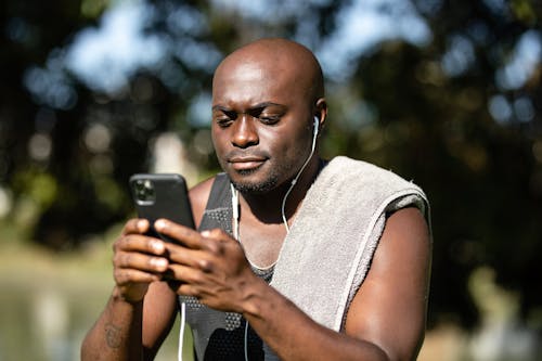 Free Close-Up Shot of a Man Listening to Music while Using a Mobile Phone Stock Photo