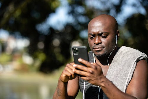 Close-Up Shot of a Man Listening to Music while Using a Mobile Phone