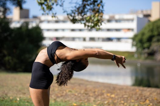 A woman exercises outdoors, performing stretching poses in a sunny urban park with blurred buildings in the background.