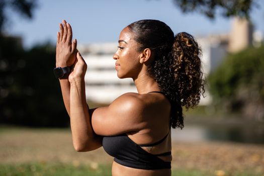 Side view of a woman practicing yoga outdoors, promoting wellness and relaxation.