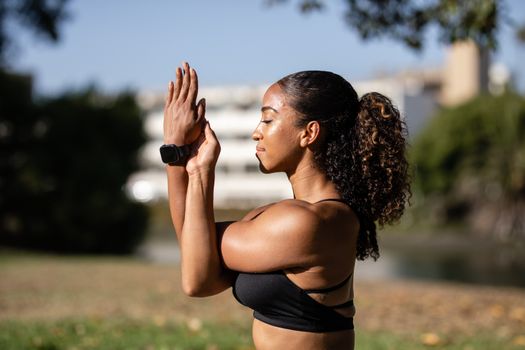 Side view of a woman meditating outdoors, embodying relaxation and wellness.