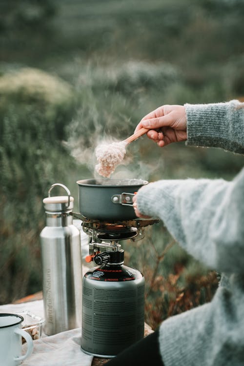 Free A Person Cooking Oatmeal using Portable Stove Stock Photo