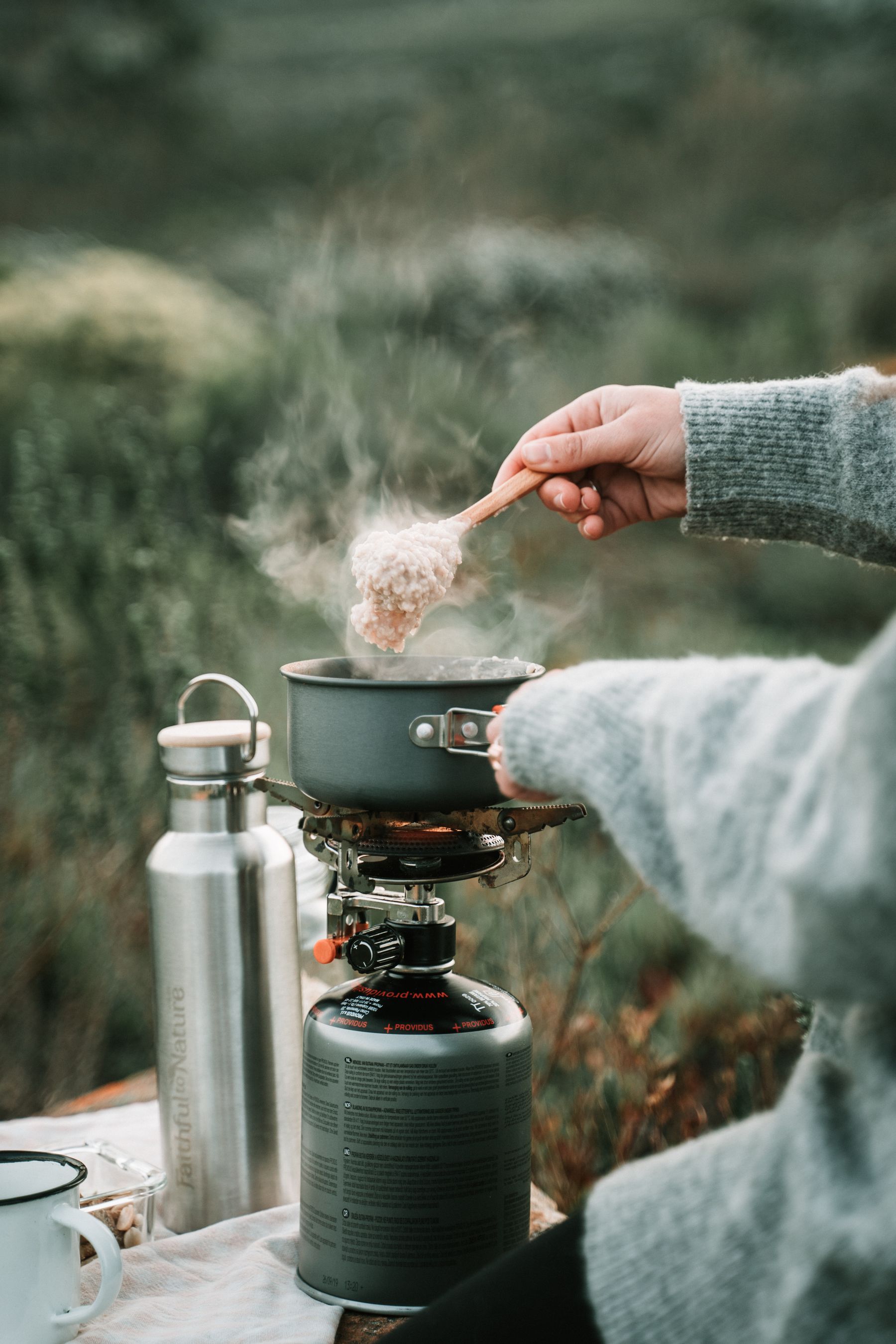 Camper preparing a meal with cookware on a portable outdoor stove