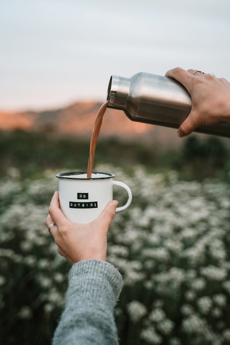 A Person Pouring Coffee In The Mug