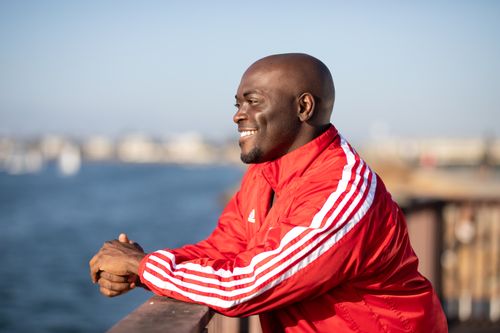 Free Happy man in a red jacket enjoying a sunny day by the waterfront. Stock Photo