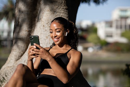 Woman in Black Sports Bra Smiling While Texting