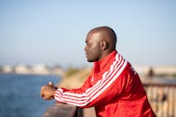 一个穿着红色夹克的男人靠在栏杆上的轮廓，背景是户外