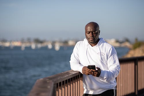 Person in White Hoodie Holding a Cellphone