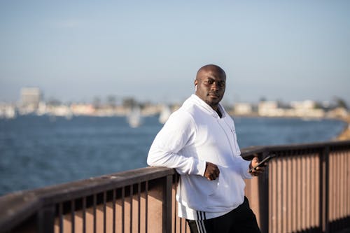 Man in White Hoodie Leaning on Railing