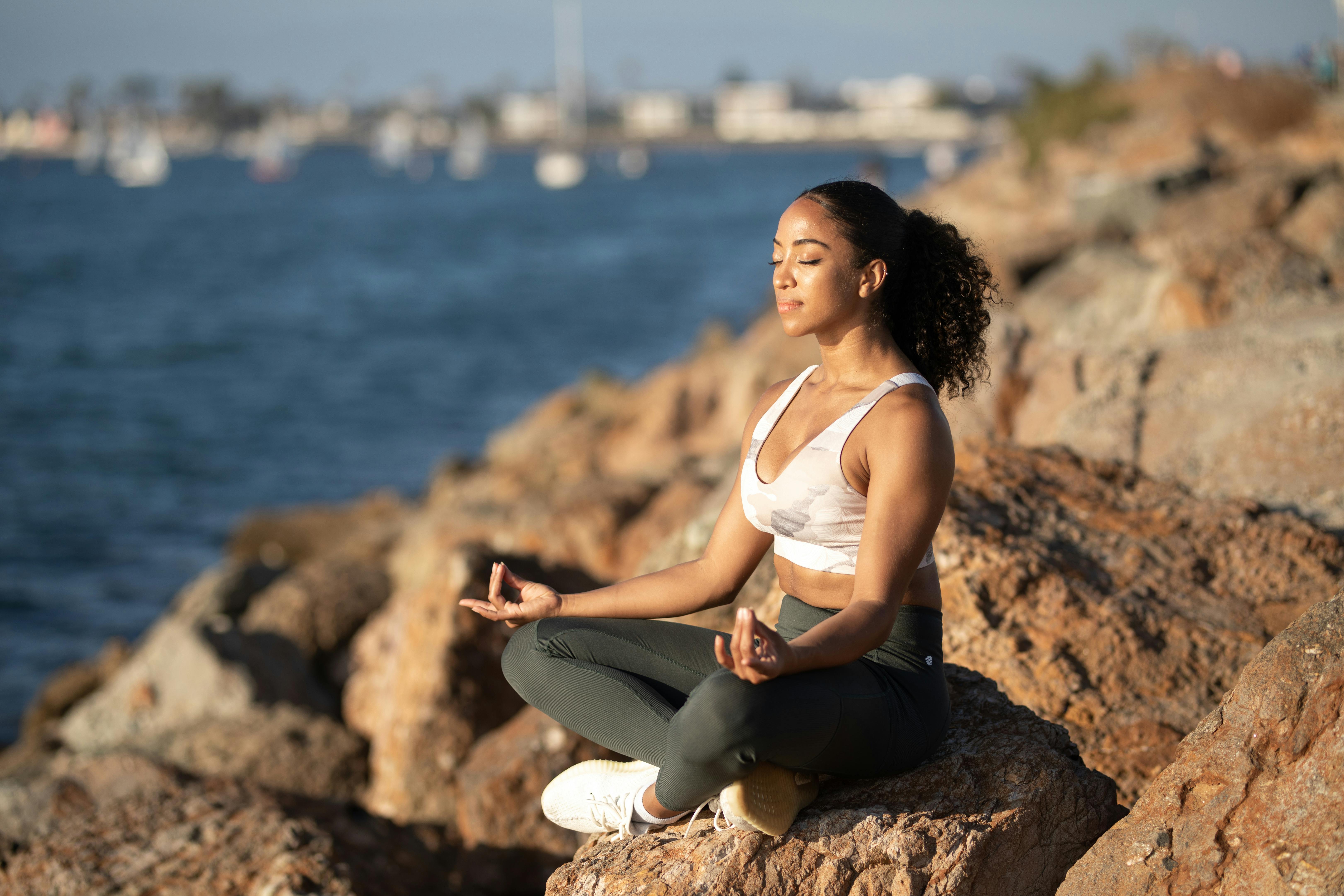 woman sitting on rock while doing yoga