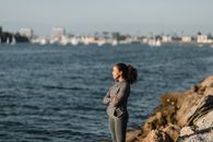 一位年轻女子双臂交叉，站在海边，面对着平静的大海