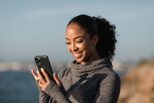 Free Young woman enjoying a mobile phone in a relaxed outdoor setting. Stock Photo