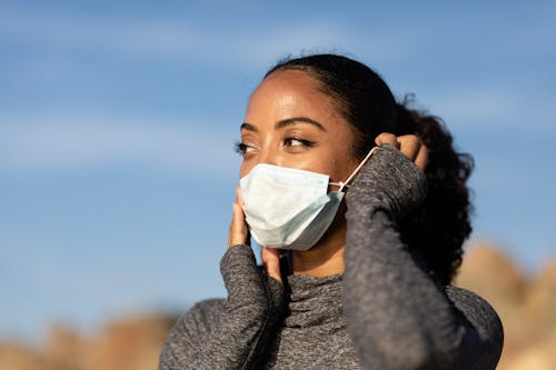 Woman in Gray Sweater Wearing White Mask