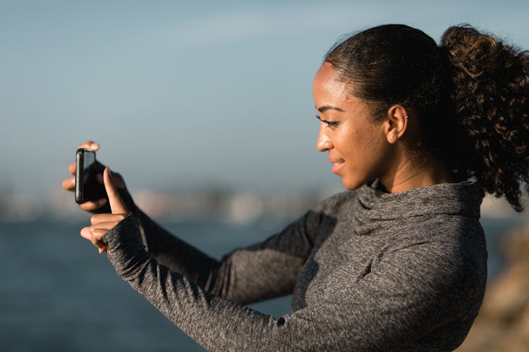 Side View Of A Woman Taking Pictures With Her Cellphone