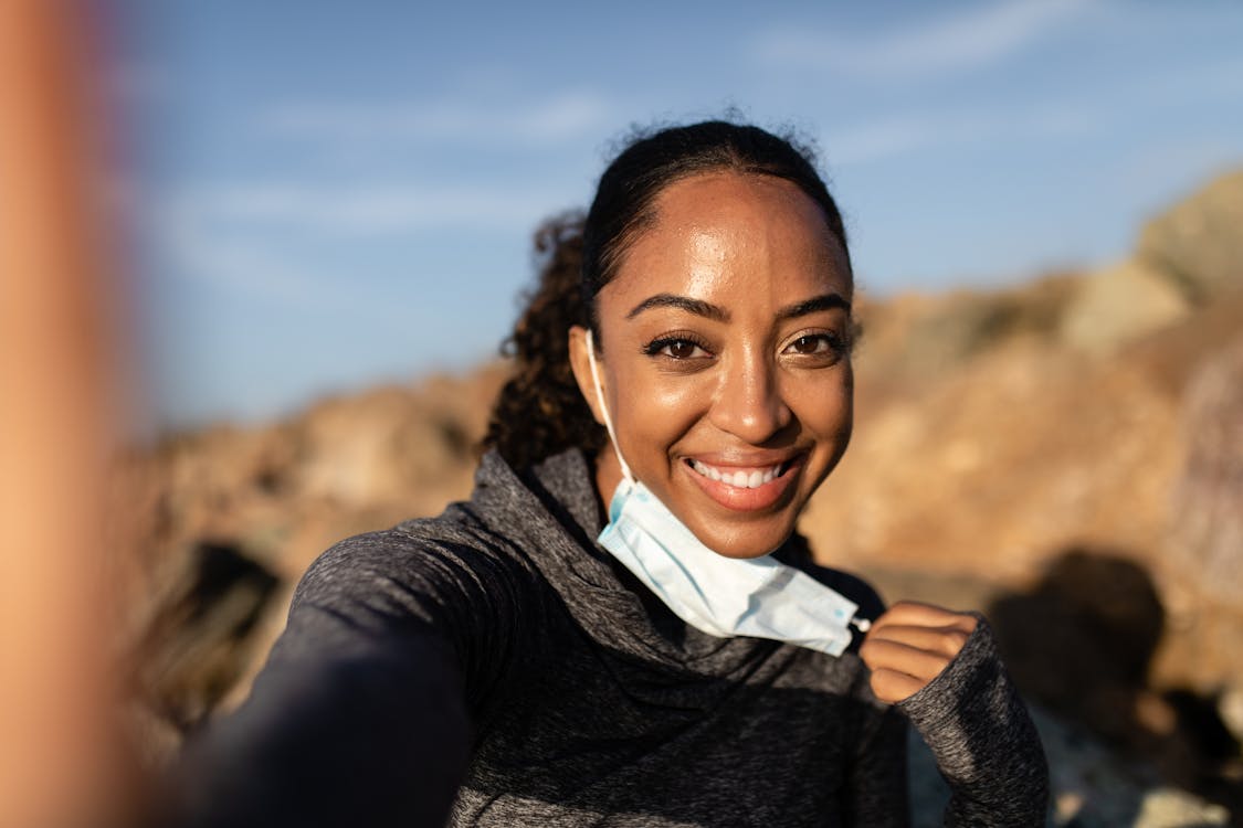 Woman in Black Long Sleeve Shirt Smiling While Taking Off Face Mask