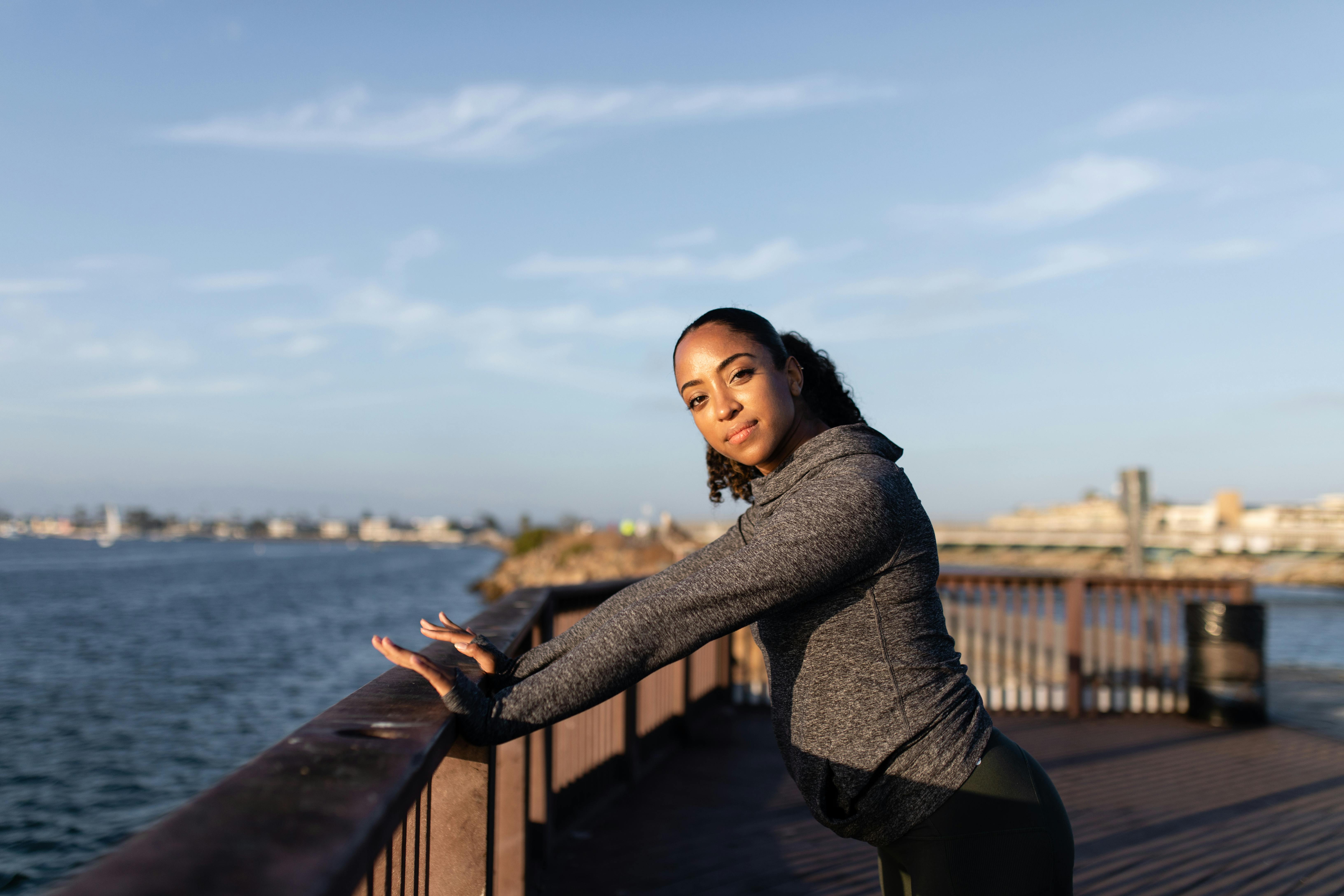 Free: woman wearing brown leggings standing near body of water