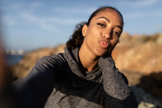 一位年轻女子身穿灰色毛衣，在户外嬉戏地摆出亲吻的姿势