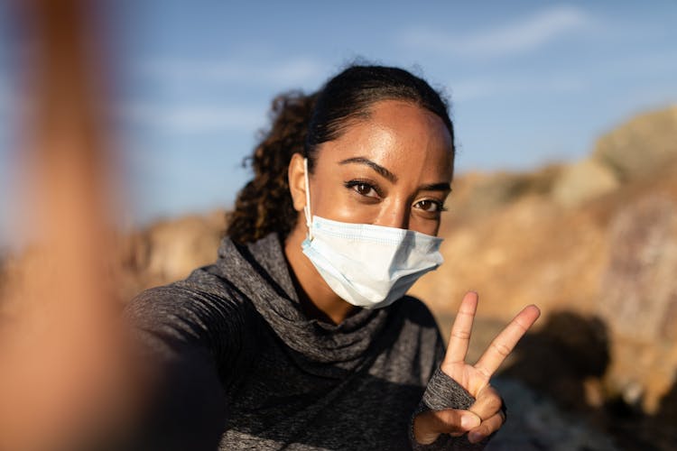 A Woman With Face Mask Taking Selfie