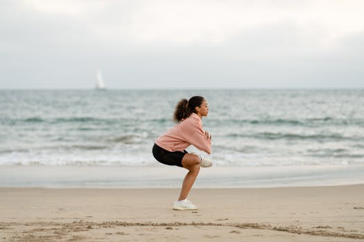Woman performing yoga on a serene beach with ocean waves in the background.