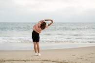 女子在海滩上做伸展运动，享受平静的海景