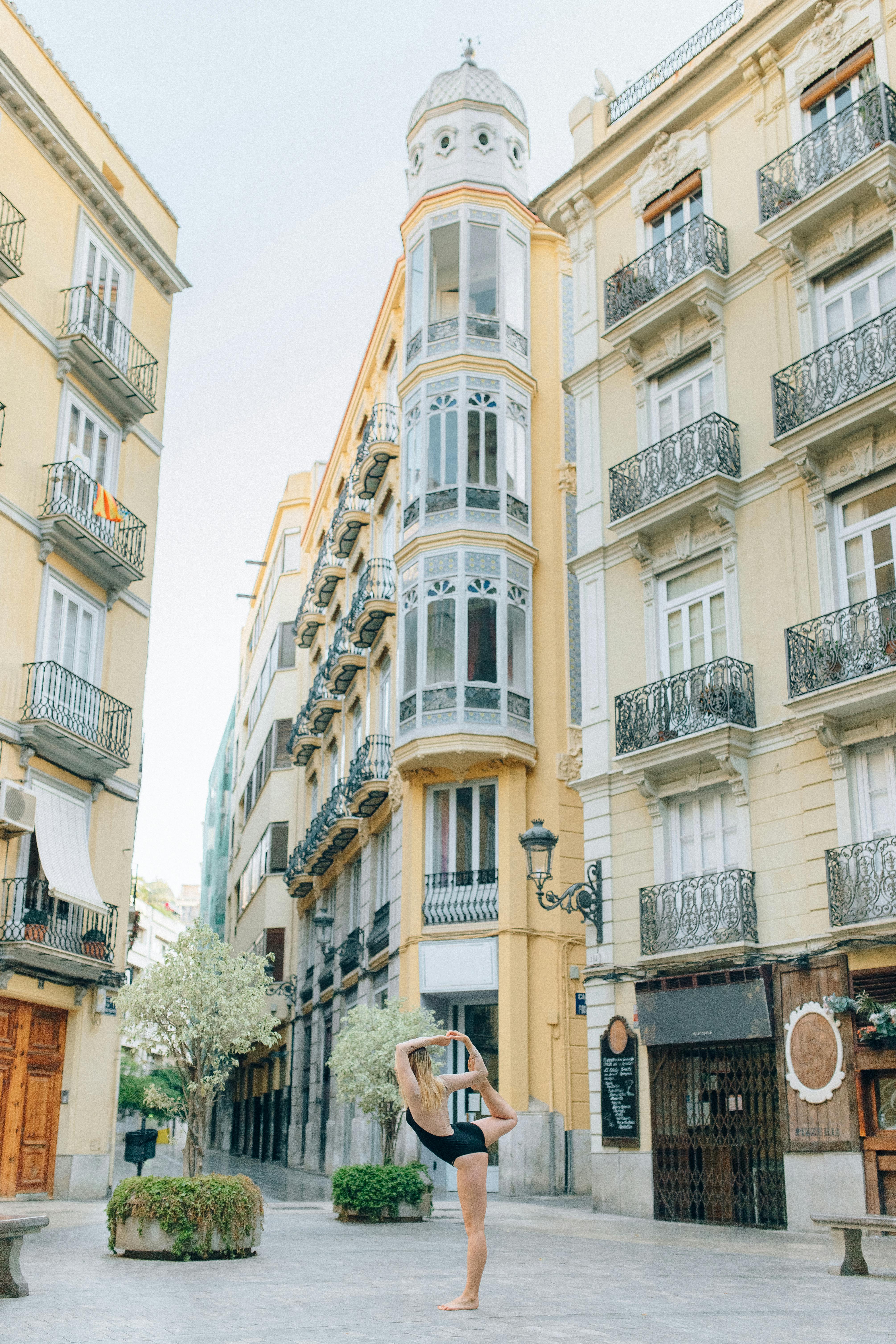 A young woman performs yoga in a picturesque European square, flanked by classic architecture.