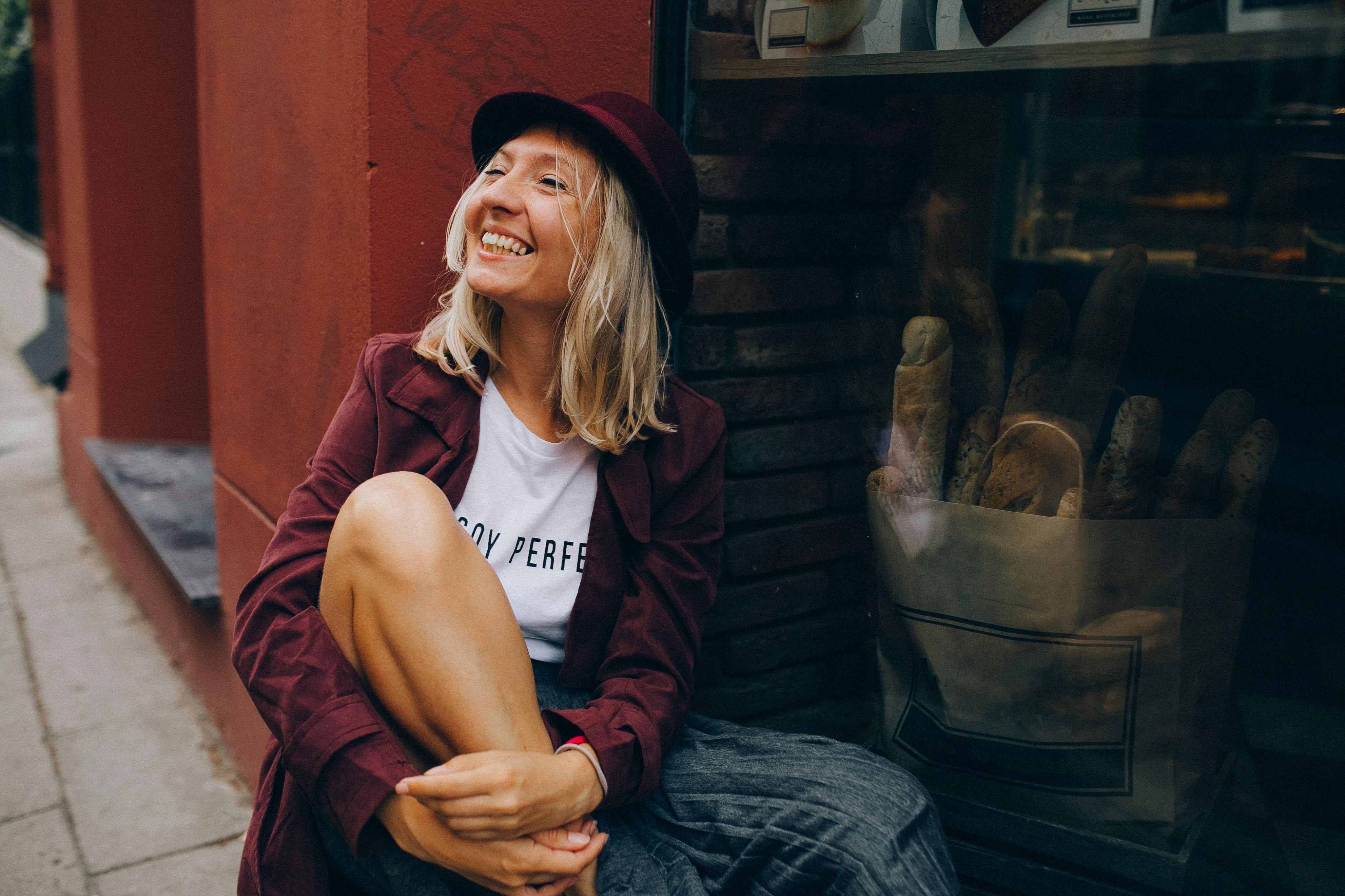 一位快乐的女士坐在面包店的窗边，享受着轻松的城市氛围