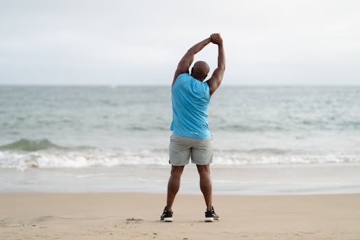 A man stretches on a beach, symbolizing fitness and a healthy lifestyle.