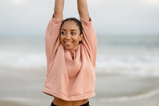 Smiling woman stretching on the beach, embodying a healthy and active lifestyle.