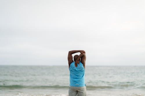 Backview of Man on Shore doing Stretching Exercises