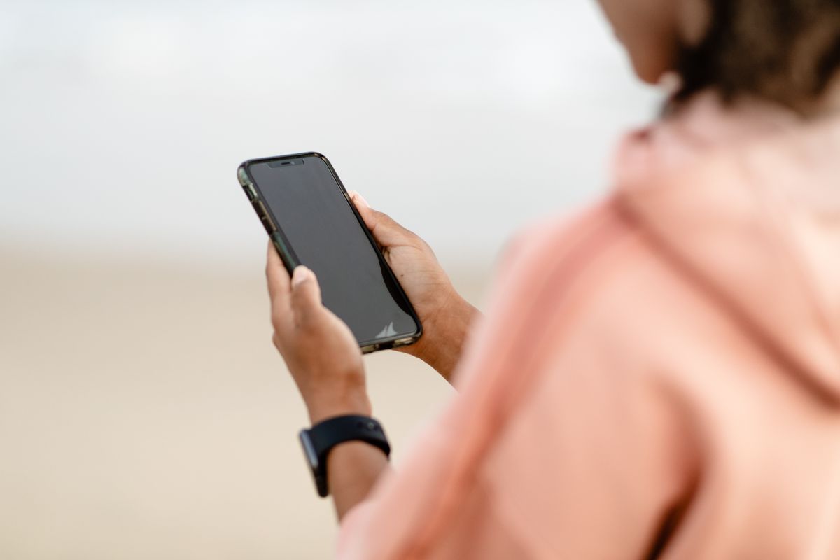 Elinde akıllı telefon tutan kişi spor maçı takip ediyor