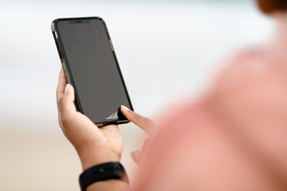 Hand houdt een smartphone vast buiten op een zonnige dag