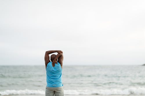 Backview of Man on Shore doing Stretching Exercises