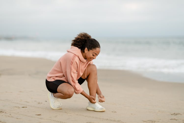 Woman In Pink Jacket Tying Her Shoes 