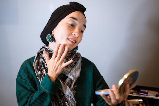 Woman applying skincare with a cheerful expression indoors, holding a mirror.