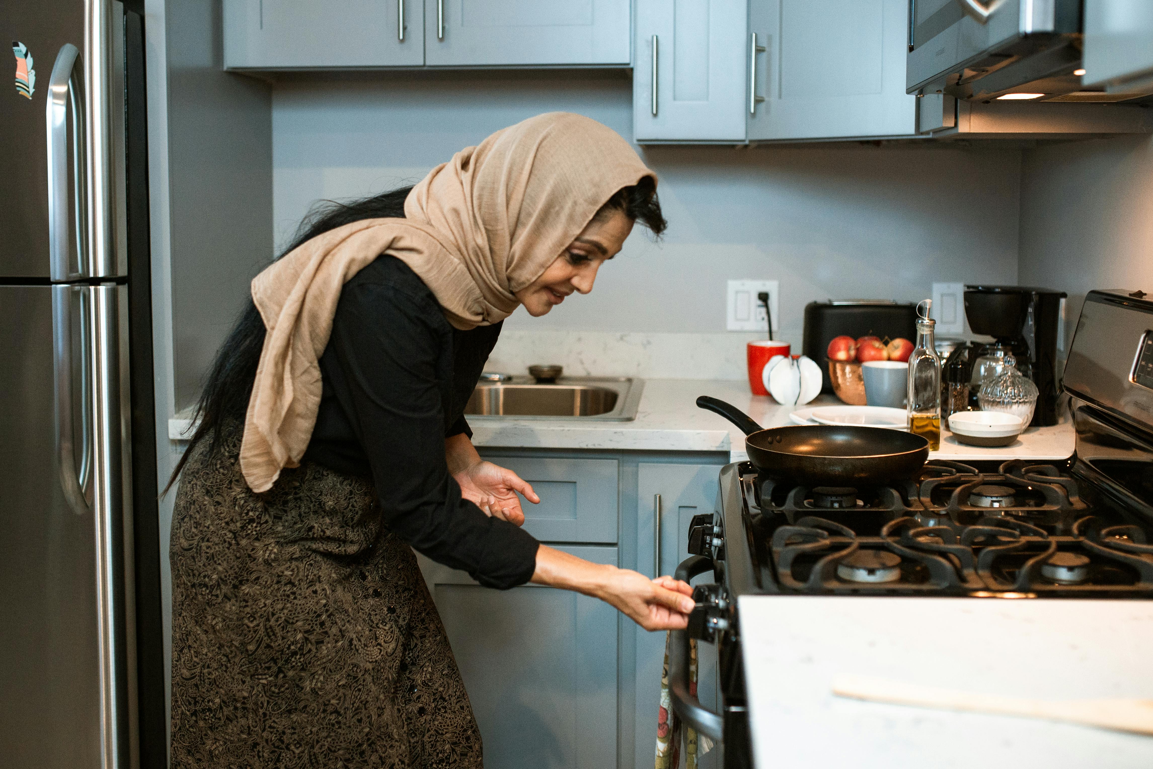 cheerful ethnic woman switching stove before cooking