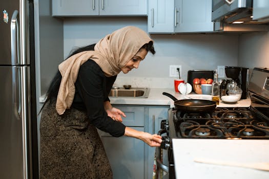 Woman wearing a headscarf cooking in a contemporary kitchen setting.