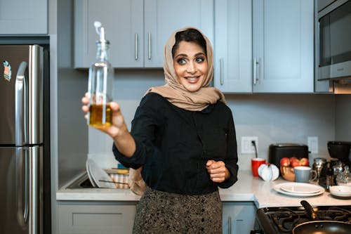 Cheerful Ethnique Femme Montrant Une Bouteille D'huile