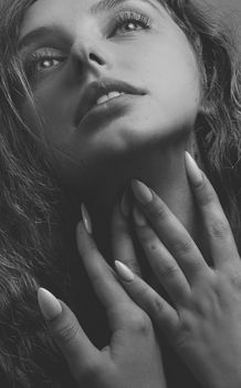 Artistic black and white portrait of a woman with manicured nails, showcasing elegance and beauty.