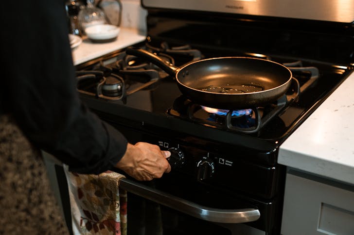Crop faceless woman adjusting rotary switch of stove