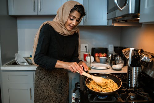 Femme En Chemise à Manches Longues Noire Et Hijab Gris Tenant Une Louche En Bois Marron