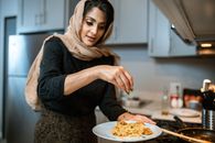 A Woman Garnishing Her Rice and Meatballs Dish