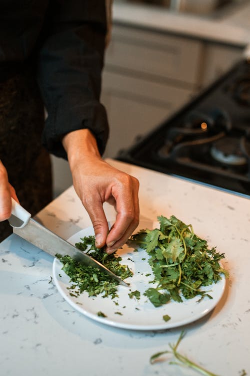 Person Holding Knife Slicing Green Vegetable